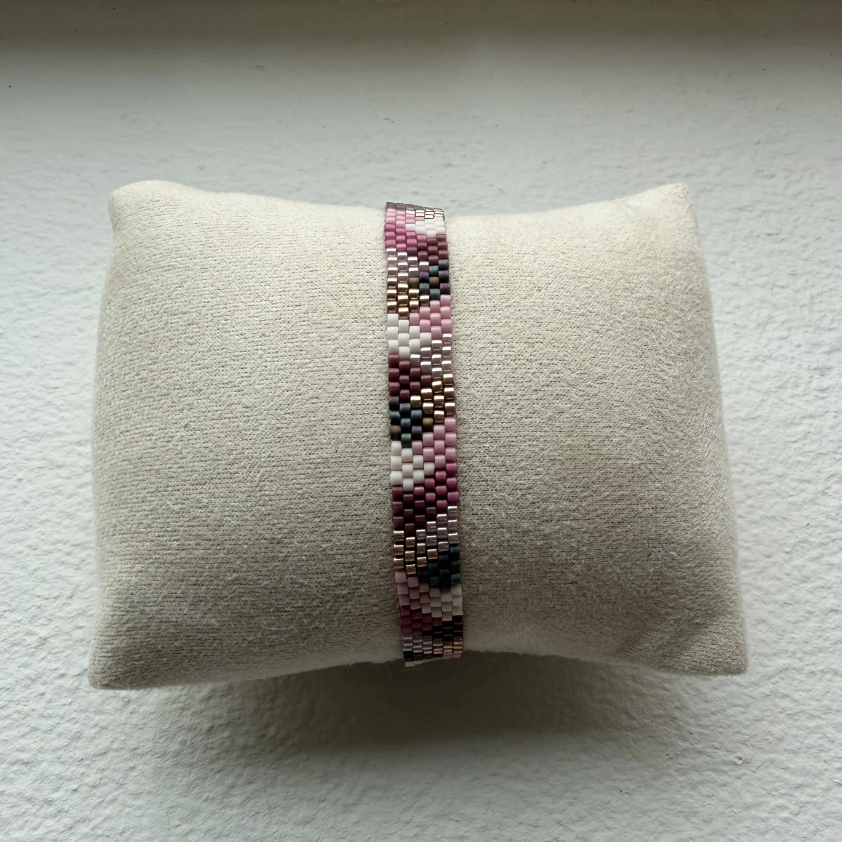 Håndsyet armbånd med lilla og rosa perlemønster